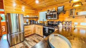 A wooden cabin interior with a kitchen featuring a stainless steel refrigerator, a microwave, and a stove. - Summer Deals/Amazing Views/Dollywood/Pet Friendly (Sevierville)