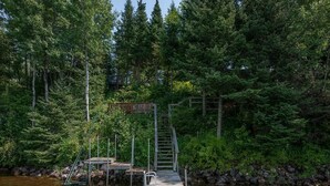 A wooden dock leading to a small wooden platform surrounded by dense forest. - Fence Lake Retreat w/ dock (Lac du Flambeau)