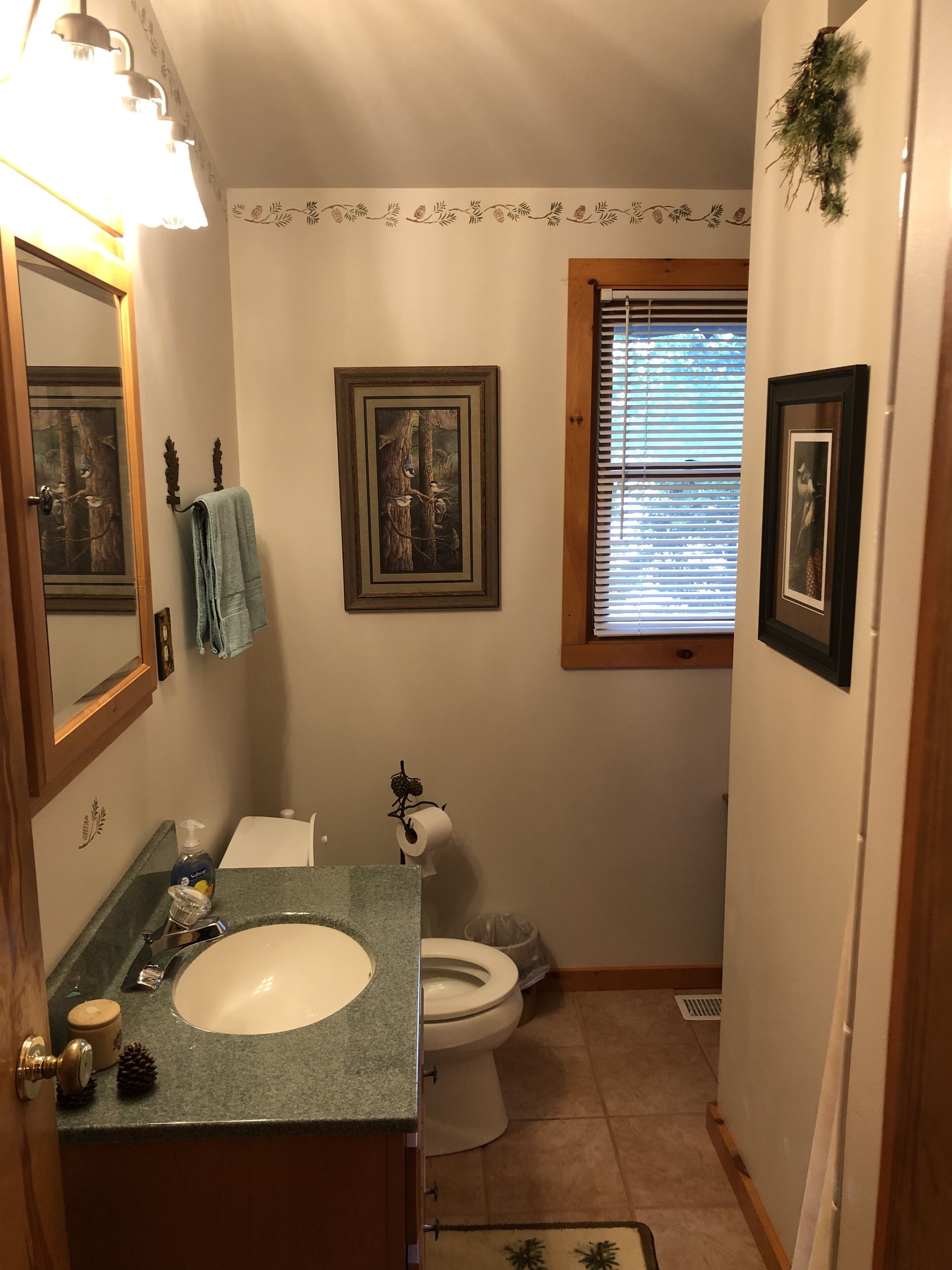 A compact bathroom with a sink, toilet, and framed pictures on the walls.