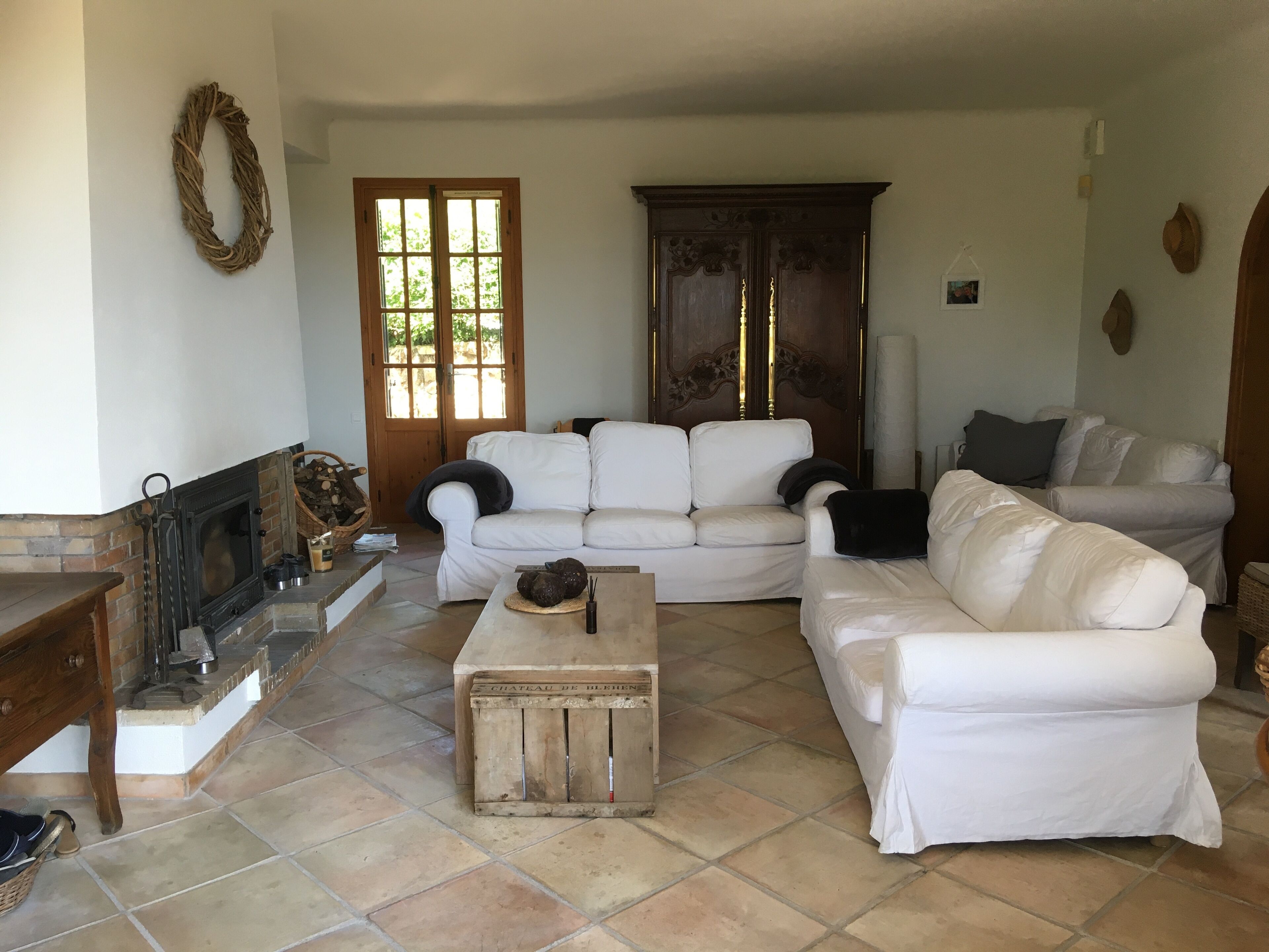 A living room with a fireplace, two white sofas, a wooden coffee table, and a large wooden door.
