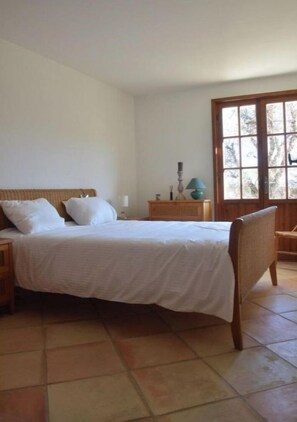 Une chambre à coucher avec un lit, des tables de chevet, une chaise et une fenêtre.