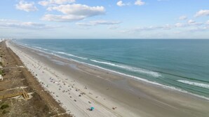 Ein Strand mit einer weiten Sandfläche und freiem Blick auf den Ozean.