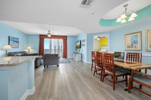 A modern living room with a sofa, coffee table, and dining area with chairs and a table.