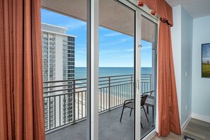 A balcony with a view of the ocean and a high-rise building.