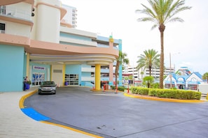 A hotel entrance with a curved facade, multiple floors, and a parking area.