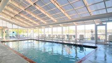 An indoor swimming pool with clear glass walls, a tiled floor, and a view of the outside.