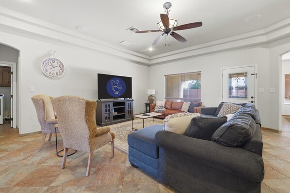 A living room with a ceiling fan, a flat-screen TV, a sofa, and a coffee table.