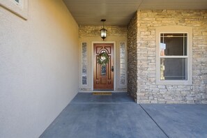 A stone exterior wall with a wooden door and a welcome mat.