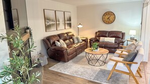 A living room with two brown leather sofas, a wooden coffee table, and a side table with a lamp. - 5 min walk to village and slopes! Peaceful 3 BR 2 Bath retreat (Snowshoe)