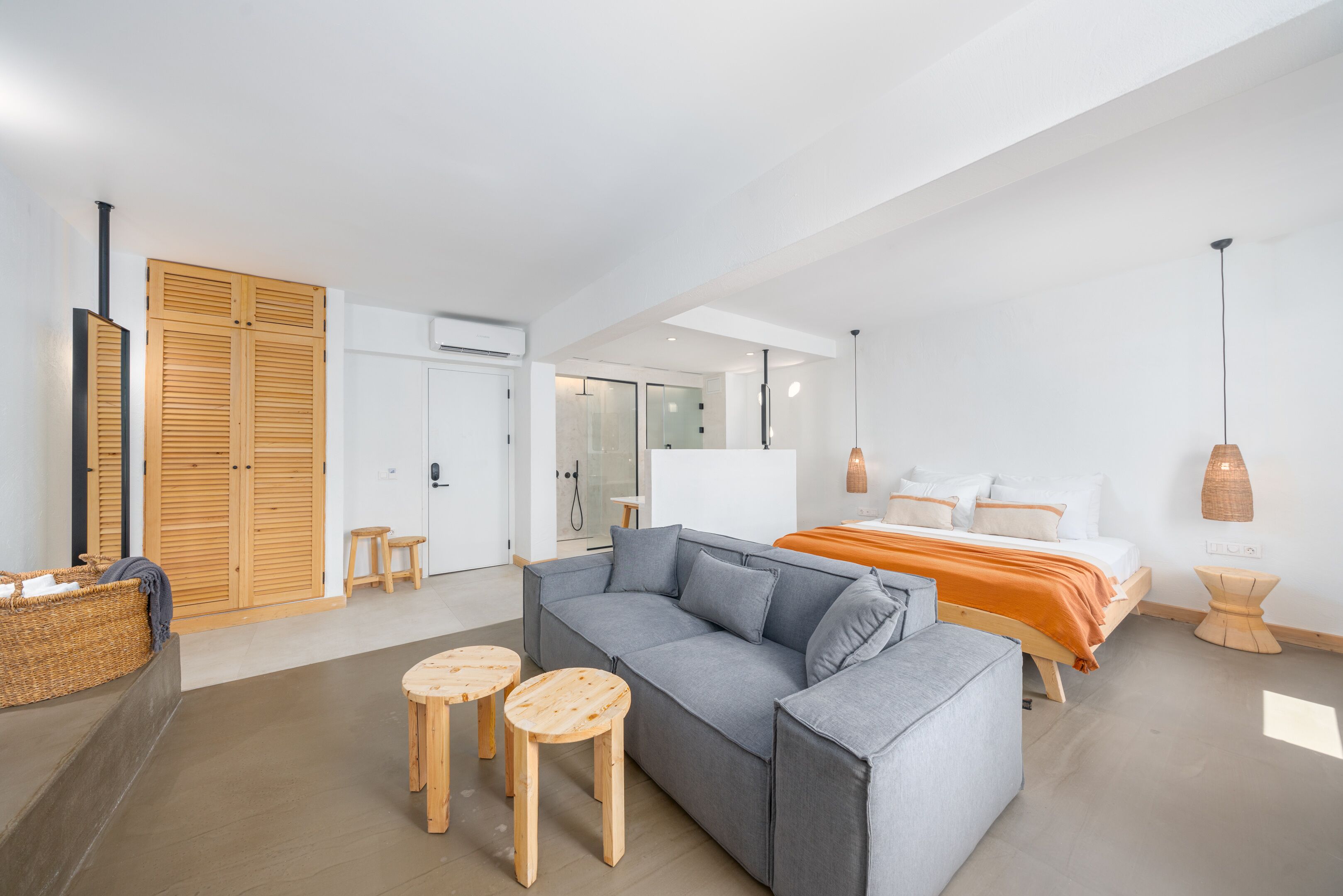 Un dormitorio moderno con un sofá gris, una cama de madera y una pequeña mesa de madera.