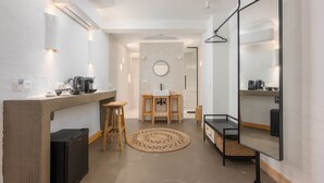 Una cocina compacta con refrigerador, cafetera y un taburete de madera.