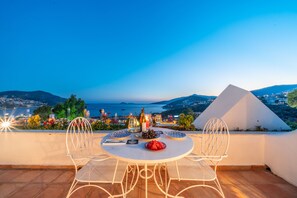 A terrace with a round table set for two, overlooking a scenic view of the sea and mountains. - Kalkan Han Hotel (Kas)
