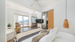 Un dormitorio moderno con una cama grande, un ventilador de techo, un televisor y vistas al exterior.