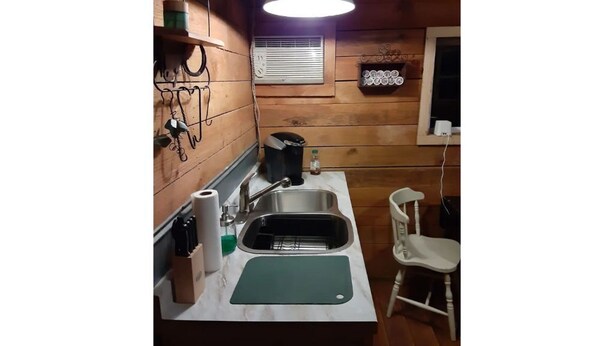 A compact kitchen with a sink, countertop, and a hanging light fixture.