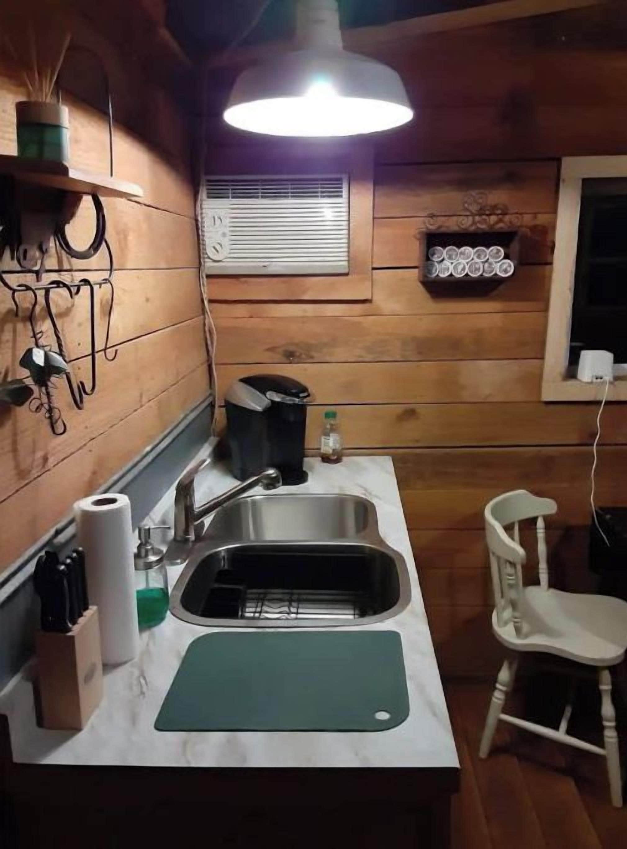 A compact kitchen with a sink, countertop, and a hanging light fixture.