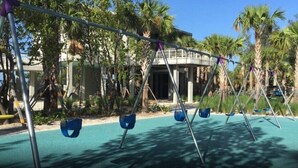Ein Spielplatz mit Schaukeln und einem Gebäude im Hintergrund.