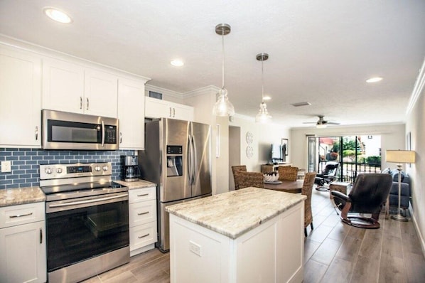 A modern kitchen with stainless steel appliances, a central island, and a dining area with a view.