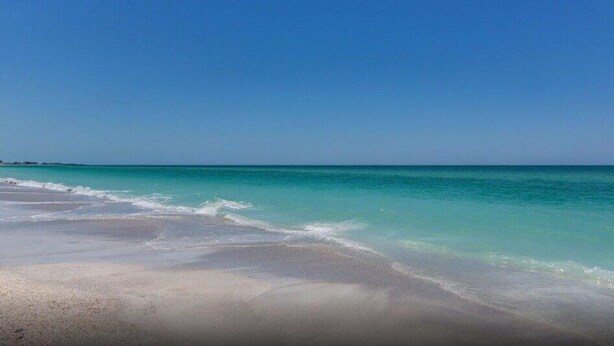 Ein Strand mit klarem türkisblauem Wasser und einem Sandstrand.