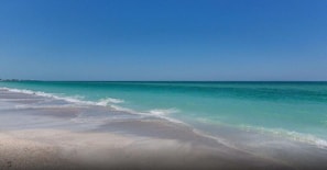 A beach with clear turquoise water and a sandy shore.