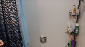 Een badkamer met een toilet, bad en een plank met toiletartikelen.
