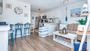 A modern kitchen with white cabinets, a central island, and bar stools.