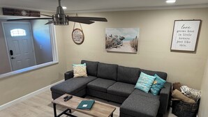 A living room with a sectional sofa, a coffee table, and a ceiling fan. - Crystal Beach Cozy Cottage - Your Perfect Vacation Escape! (Palm Harbor)