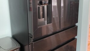 A stainless steel refrigerator with a water dispenser, located in a kitchen with light blue walls and tiled flooring. - Crystal Beach Cozy Cottage - Your Perfect Vacation Escape! (Palm Harbor)