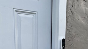 A white door with a modern electronic lock and a keyhole. - Crystal Beach Cozy Cottage - Your Perfect Vacation Escape! (Palm Harbor)