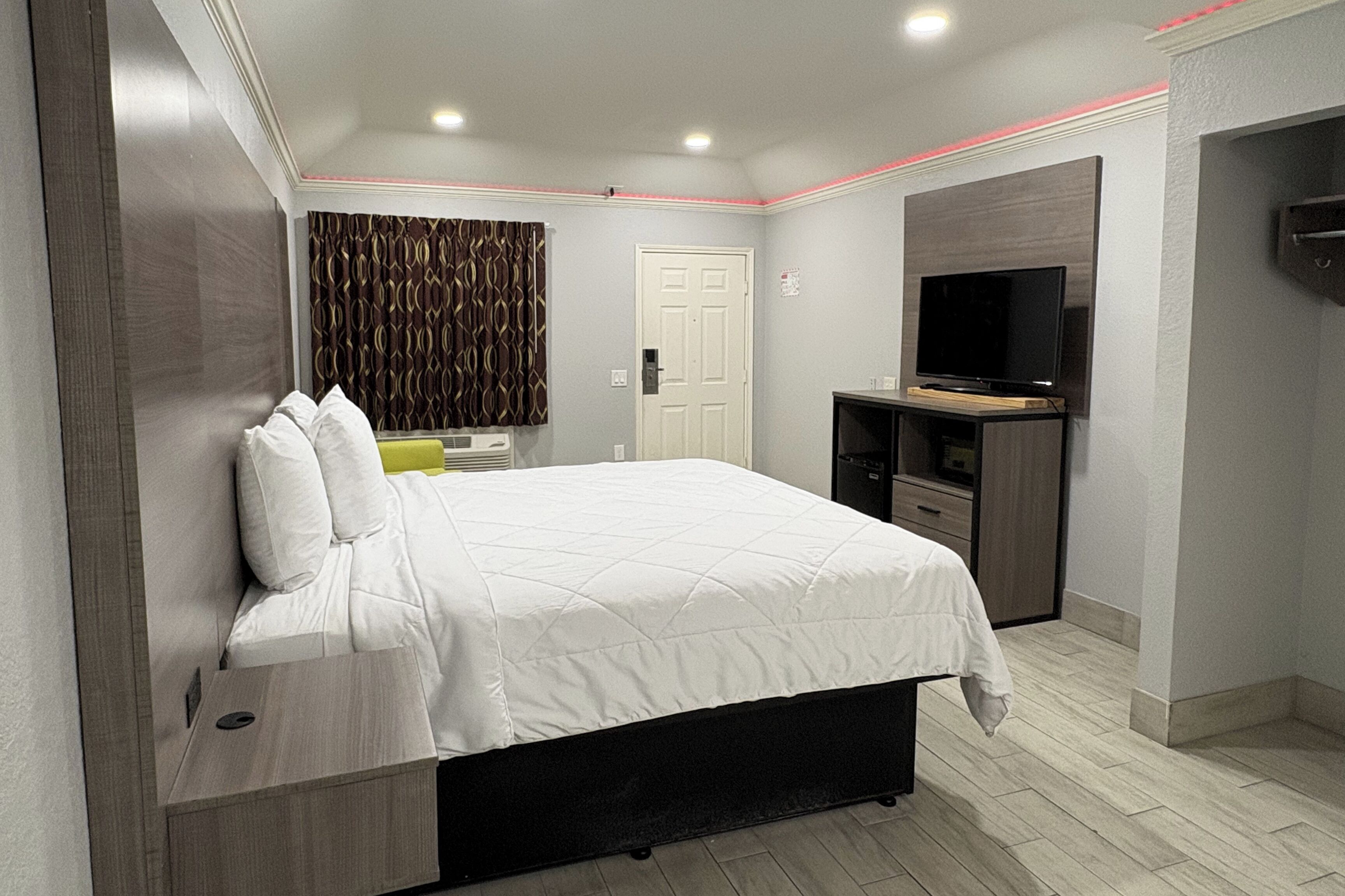 Una habitación de hotel moderna con una cama grande, un televisor de pantalla plana, un escritorio y un guardarropa.