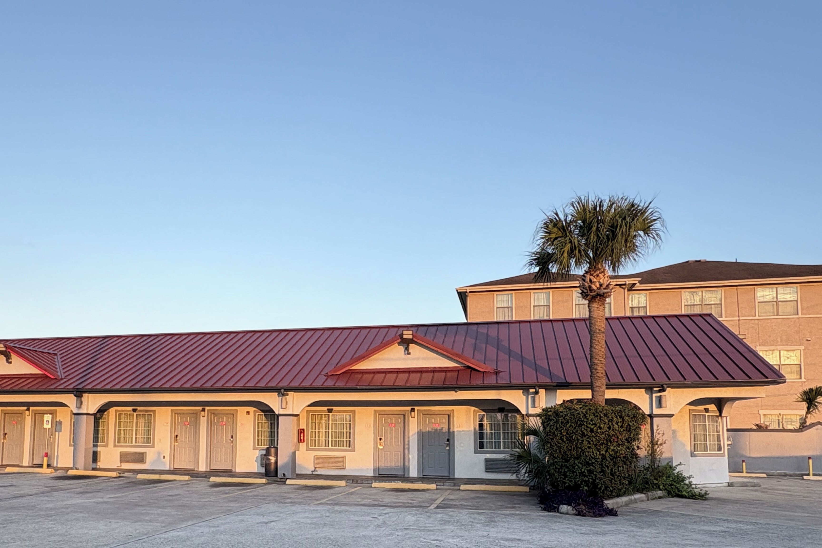 A building with a red roof and multiple doors, likely a hotel or motel.