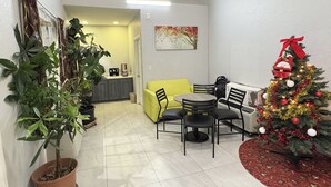 A dining area with a table and chairs, a Christmas tree, and potted plants. - Kiwi Inn Capital O Houston - Hwy 249 (Houston)