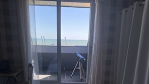 Un dormitorio con una cama grande, vistas al mar, un balcón con un telescopio y una silla.