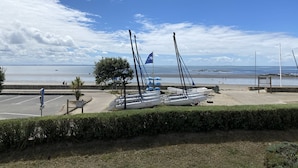 Un puerto deportivo con varios veleros amarrados, cielo despejado y mar en calma.