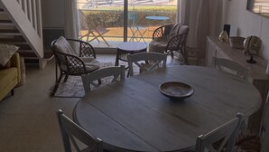 Un comedor con vistas a la playa, que incluye una mesa redonda, sillas y vista a veleros.