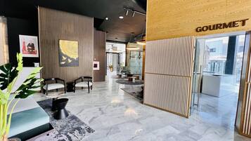 A modern lobby with a reception desk, seating area, and a 'GOURMET' sign.