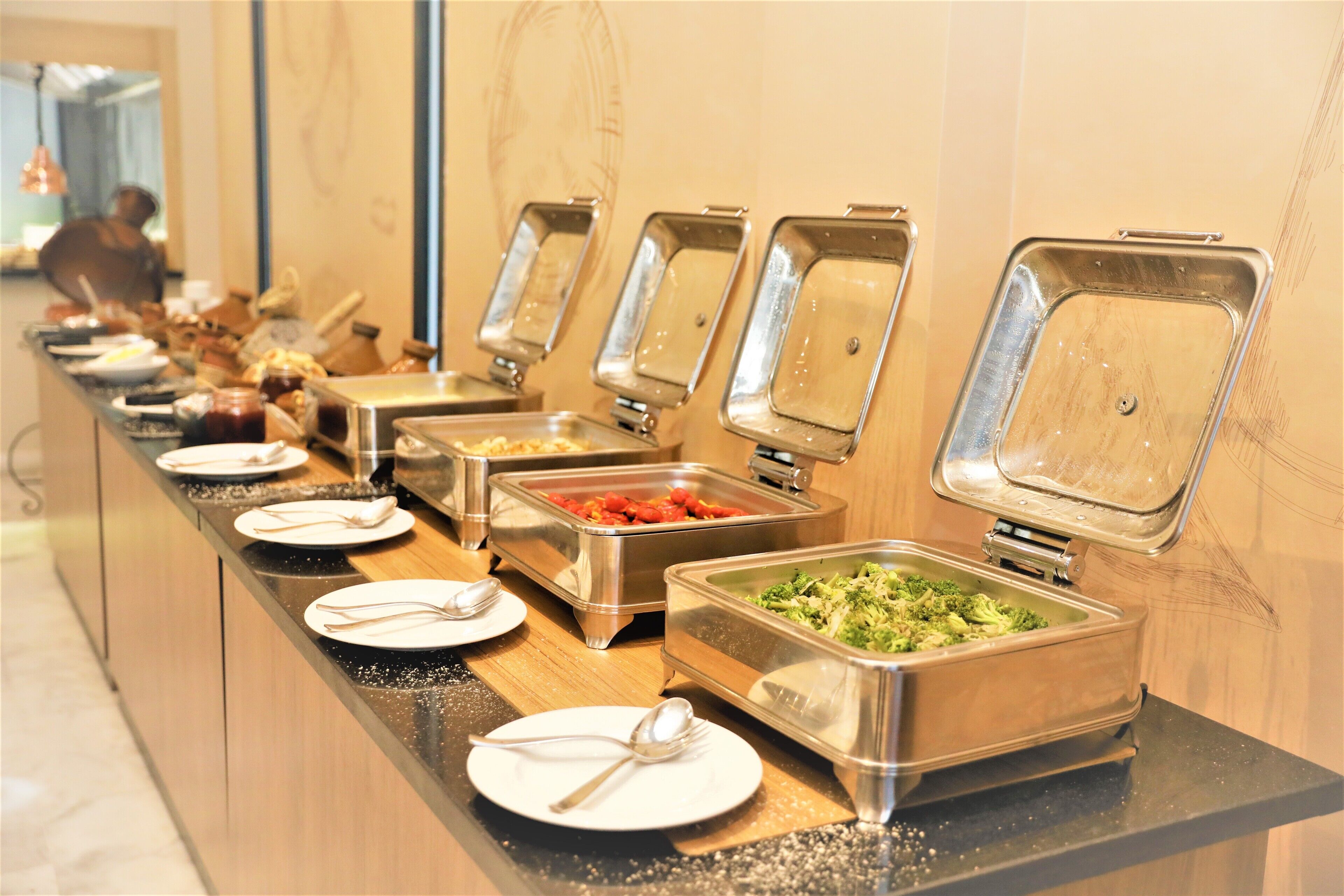 A buffet setup with various food containers and utensils.