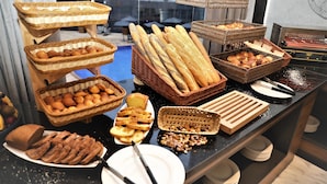 Una mesa de buffet con panes y pasteles variados exhibidos en cestas y platos.