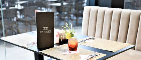 A restaurant table with a menu, a glass of iced tea with a garnish, and a placemat.
