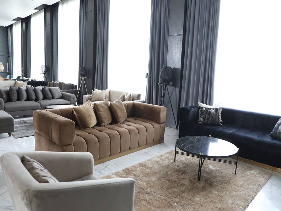 Una sala moderna con un sofá beige, un sofá azul oscuro y una mesa de centro redonda.