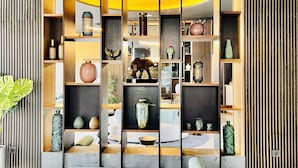 Un interior moderno con un sofá central, una mesa de centro y una estantería llena de objetos decorativos.