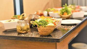Uma mesa de buffet com diversos pratos e uma cesta de legumes frescos.