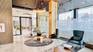 Un vestíbulo moderno con una zona de estar circular, un mostrador de recepción y grandes ventanales con vistas.