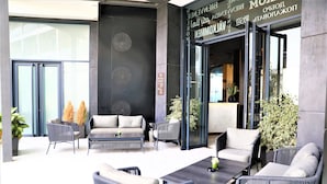 Un espacio al aire libre moderno con mobiliario de mimbre, una mesa de centro y plantas en macetas.