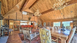 A spacious log cabin interior with a large dining table, multiple chairs, a fireplace, and a chandelier. - Fish Creek Ranch Lodge with Hot Tub and Game Room (Dolores)