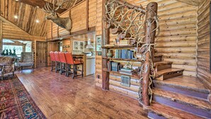 A log cabin interior with a wooden staircase, a mounted deer head, and a bookshelf. - Fish Creek Ranch Lodge with Hot Tub and Game Room (Dolores)
