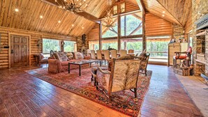 A spacious log cabin interior with a high ceiling, large windows, and a fireplace. - Fish Creek Ranch Lodge with Hot Tub and Game Room (Dolores)