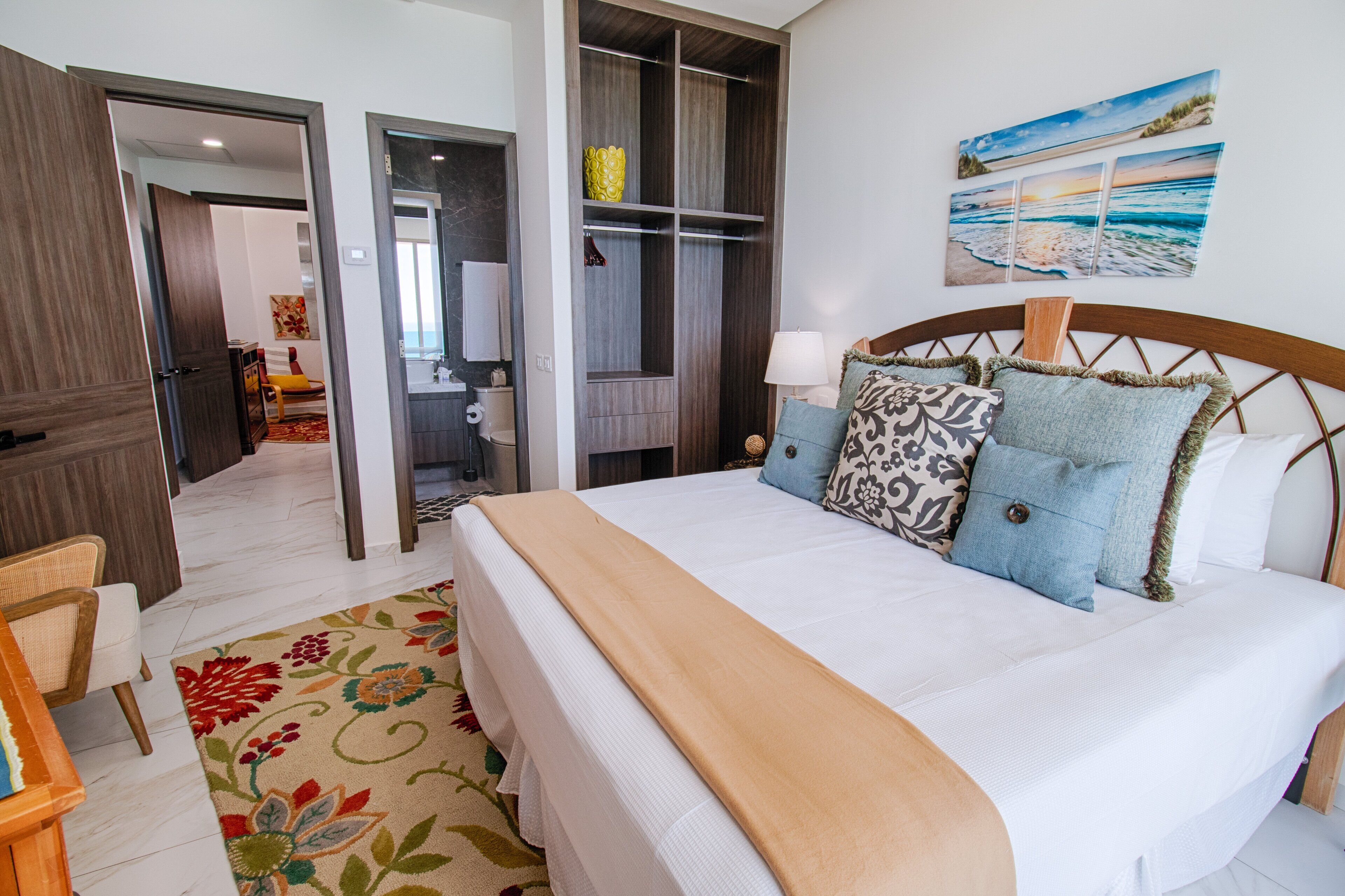 A hotel room with a large bed, a wardrobe, a bathroom, and a view of the beach.
