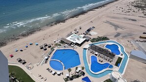 Un resort con diverse piscine, una spiaggia e vista sull'oceano.