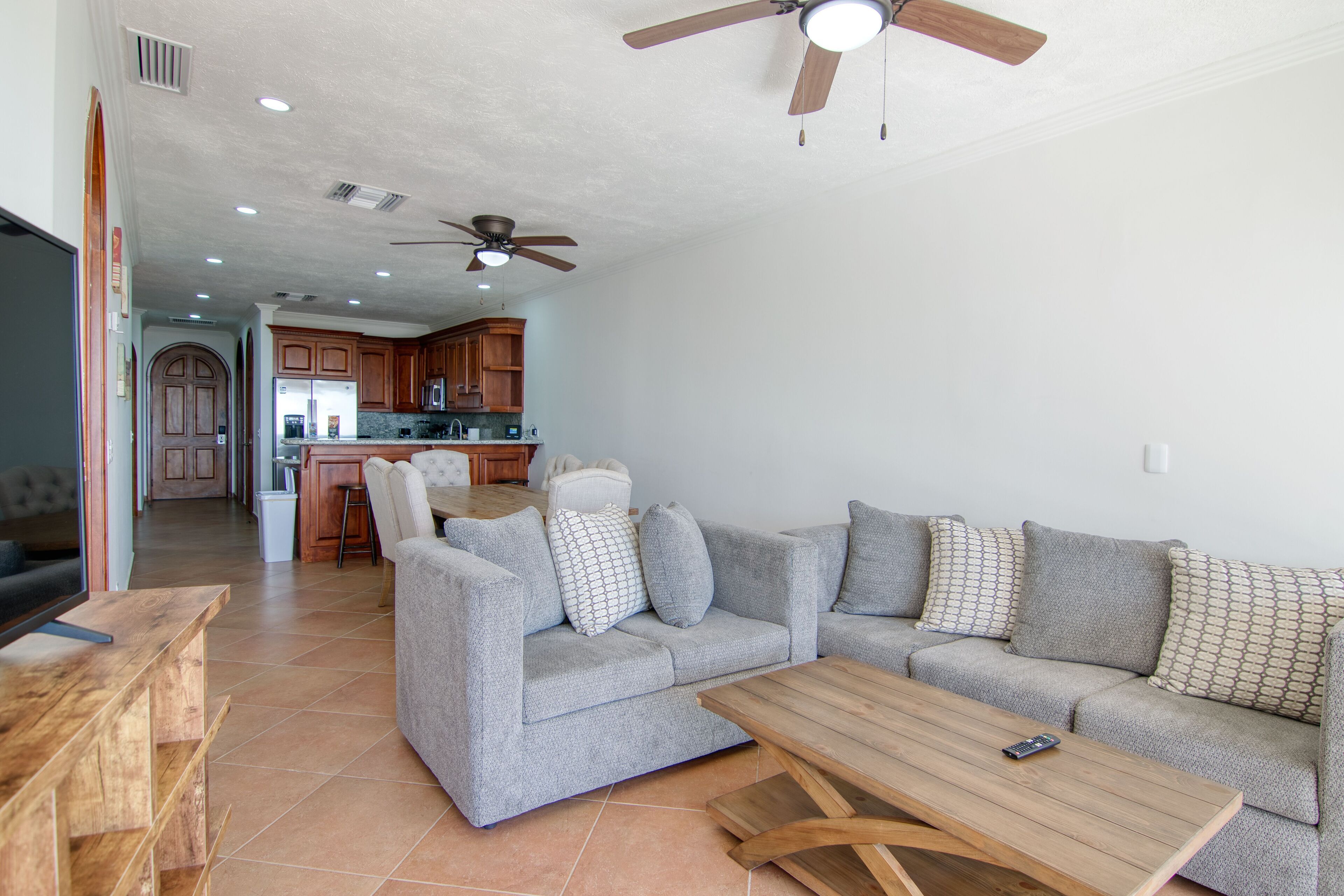 A modern living room with a grey sofa set, a wooden coffee table, and a TV on a wooden stand.