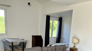 A modern living room with a grey sectional sofa, a glass coffee table, a dining area with a table and chairs, and a view of the outdoors through a window. - New house a stone's throw from the coastal path and harbours (Gujan-Mestras)